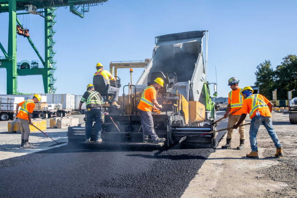 Workers prepare and pave a parking lot surface